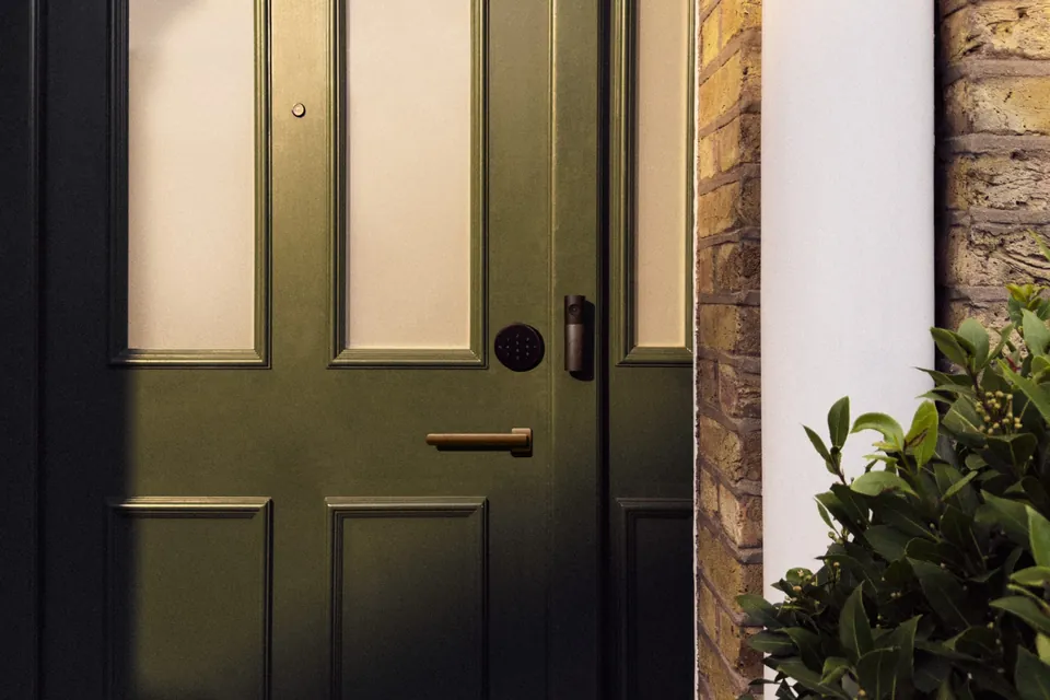 A smart deadbolt lock and video doorbell on a dark green front door