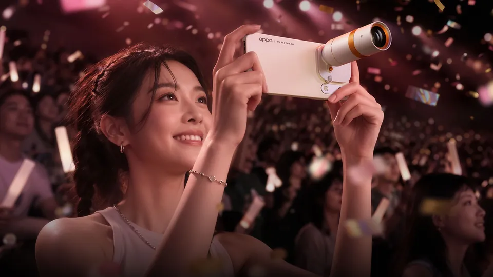 A woman at a concert films with a Find X10 Pro Max fitted with the Hasselblad teleconverter lens