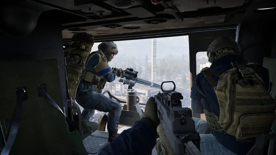WARDOGS soldiers inside a helicopter, one manning a door gun over an industrial valley