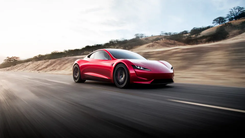 A red Tesla Roadster prototype driving on a road past dry hills