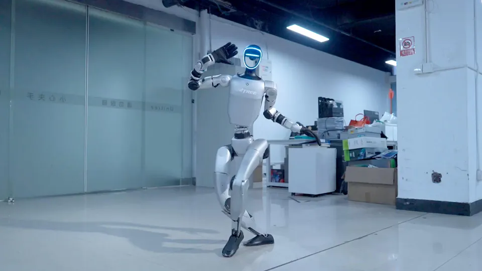 A Unitree G1 balances on one leg in an office