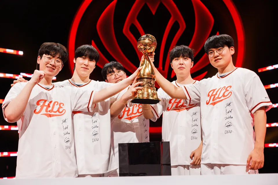 Five Hanwha Life Esports players in white jerseys lift the MSI 2026 trophy on stage after the final