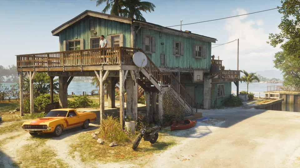 A stilt house by the water with a classic car parked underneath