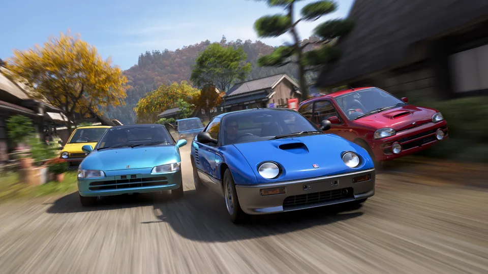 A blue sports car leads a pack of cars down a village road in autumn