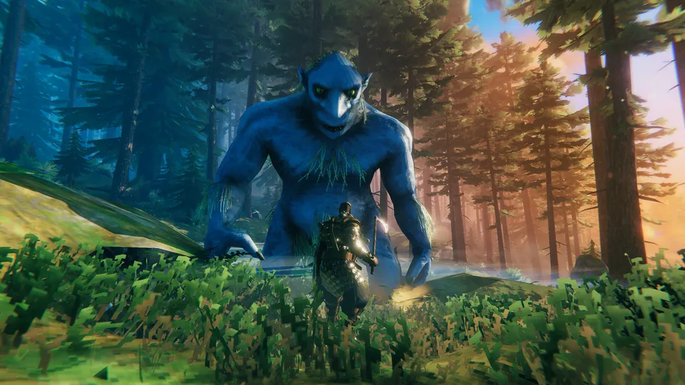 A Viking warrior in dark armor walking through tall grass in front of a huge blue troll in a sunlit pine forest