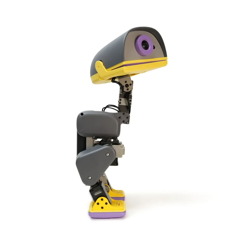 Graphite Microduck robot in profile with a yellow beak and a round camera eye