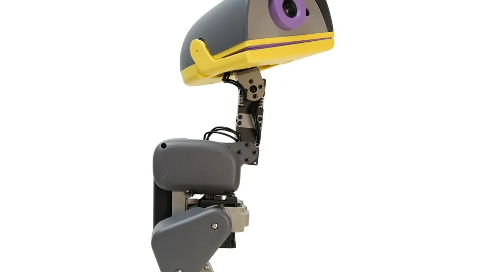 Graphite Microduck robot in profile with a yellow beak and a round camera eye