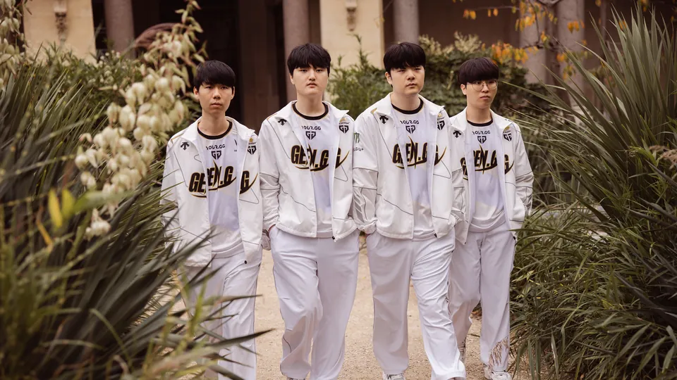 Four Gen.G players in white team jackets walk along a garden path at the Worlds 2024 semifinal photo shoot in Paris